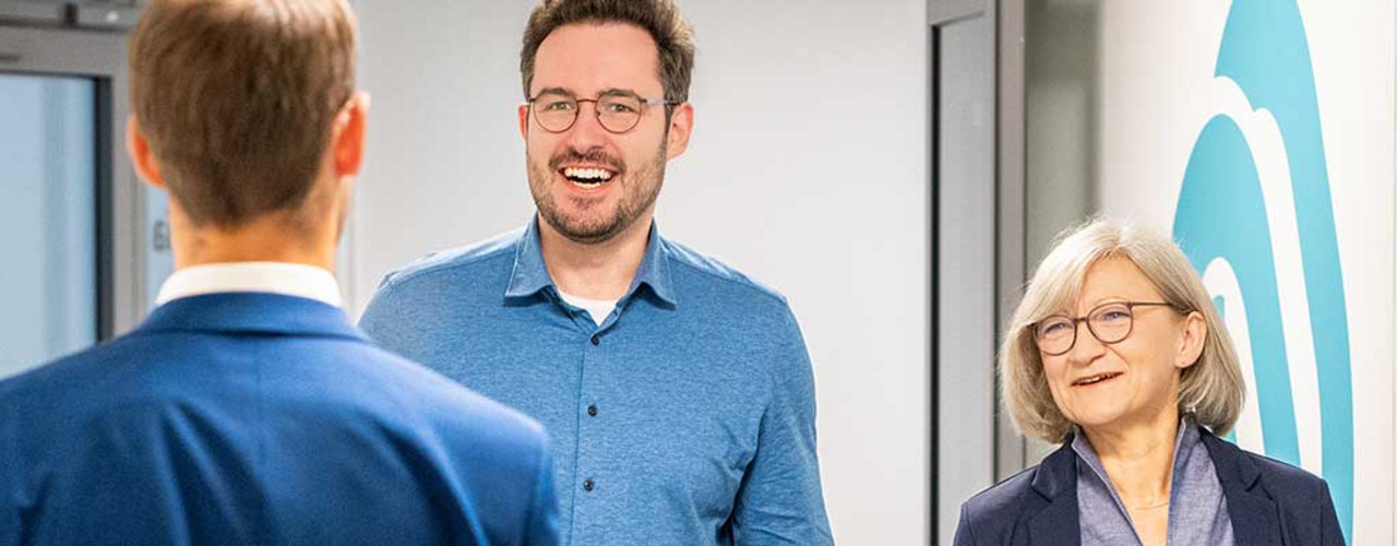Karriere Drei Personen treffen sich auf dem Flur eines Nexia-Büros.