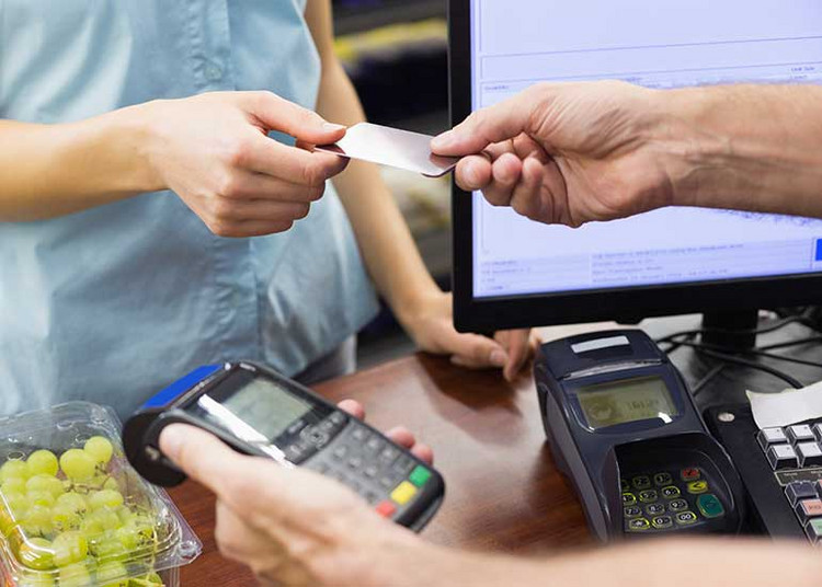 Person bezahlt mit Karte an der Supermarktkasse.