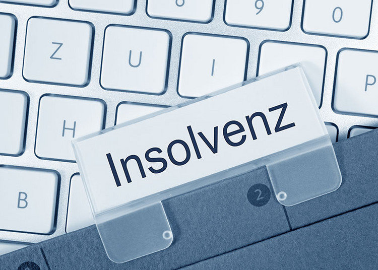 Ordner mit Reiter „Insolvenz“ liegt auf Tastatur.