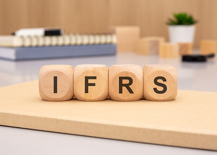 Auf einem Tisch liegen Würfel, auf denen „IFRS“ für „International Financial Reporting Standards“ steht. Jeder Buchstabe steht auf einem Würfel.