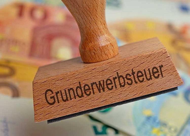 Stempel mit Auschrift "Grunderwerbsteuer" vor Euro-Scheinen.