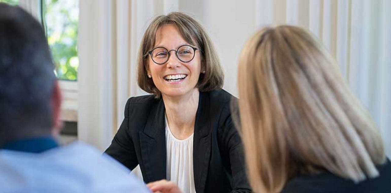 Wir leben Unternehmergeist Ein Partner sitzt locker mit Kollegen zusammen und lacht.