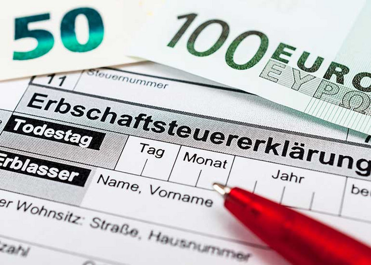 Formular „Erbschaftssteuererklärung“ neben Euro-Scheinen und Kugelschreiber.