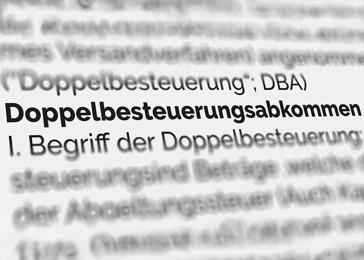 Aufsicht auf eine Seite eines Lexikons. Der Text „Doppelbesteuerungsabkommen“ ist hervorgehoben, der Rest ist weitgehend unscharf.