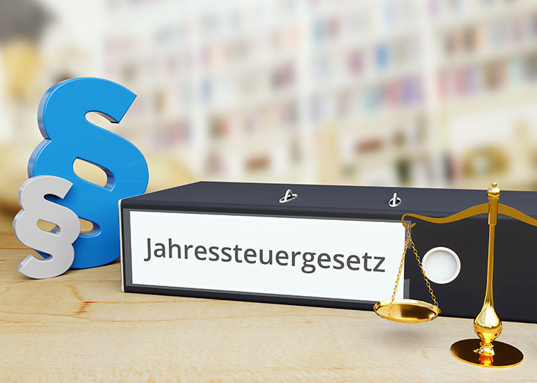 Aktenordner mit der Aufschrift "Jahressteuergesetz" daneben ist eine Waage und das Symbol §.