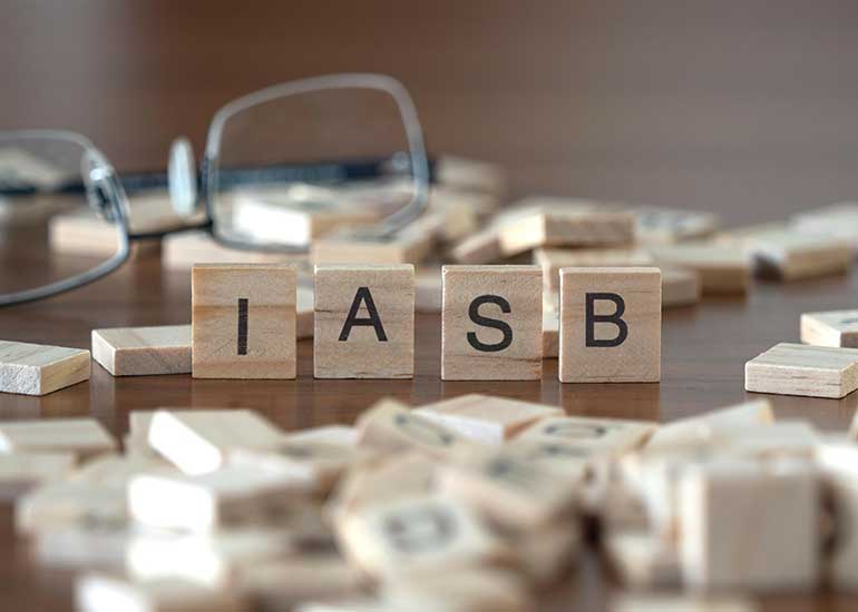 Tisch mit Scrabble-Plättchen aus Holz. Aus 4 Plättchen ist das Wort „IASB“ (für International Accounting Standards Board) gelegt.