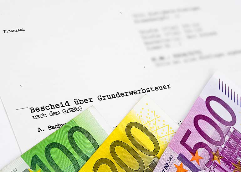 Euro-Scheine vor einem Bescheid über Grunderwerbsteuer.