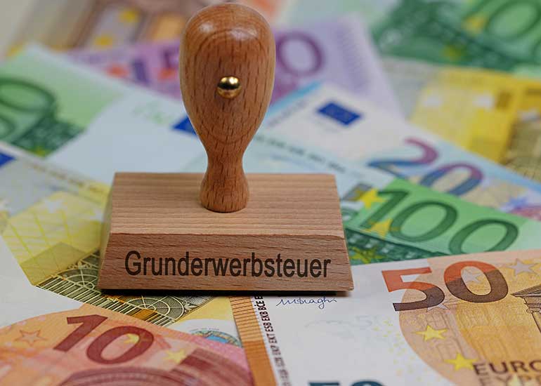 Ein Stempel mit der Aufschrift "Grunderwerbsteuer" steht auf Euro-Banknoten.